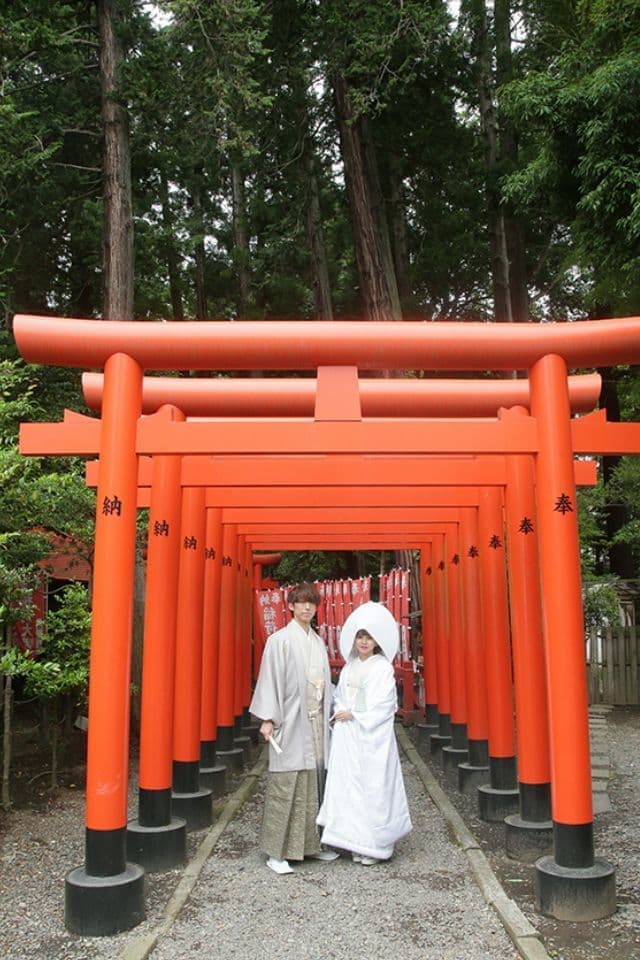 和装を着た新郎新婦が神社の鳥居の前に立っている画像