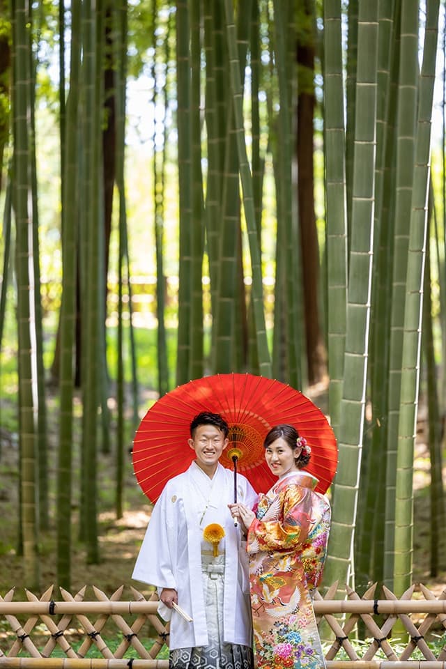 茨城県鉾田市光翔　レンタル＆フォトスタジオ。和装の新郎新婦が赤い傘を持ち正面を向いている画像